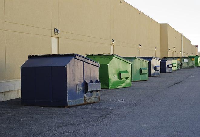 a construction worker unloading debris into a blue dumpster in Chicago Heights, IL